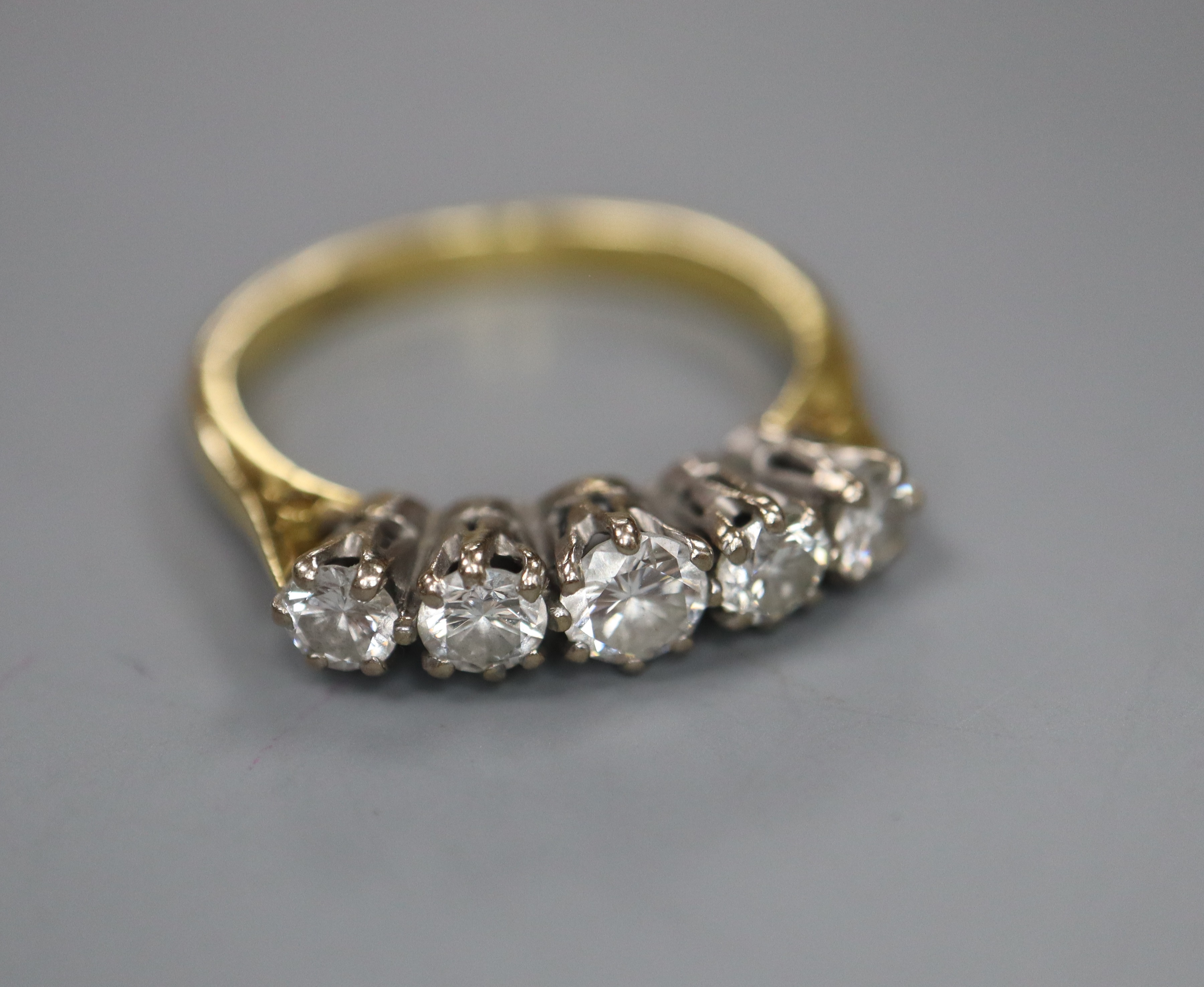 An 18ct and graduated five stone diamond set half hoop ring, size O, gross 3.6 grams.